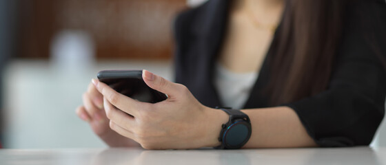 Female hands using smartphone on table in office room