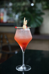 Pink Cocktail glass with ice at a bar counter