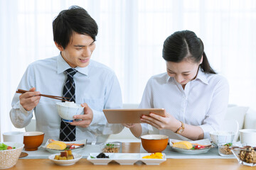 朝食を食べながらタブレットPCを見る夫婦