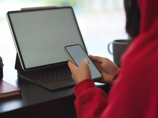 Side view of female in red sweater using mock up smartphone and tablet
