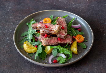 Grilled beef steak salad with arugula, potatoes, carrots, onions and pomegranate. Healthy eating. Diet.