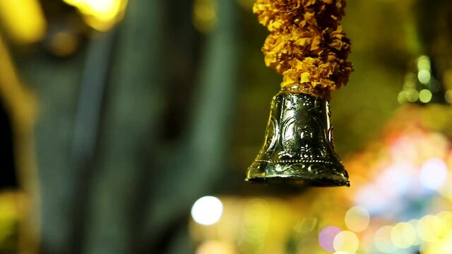 Close up of holy bell hanging on a flower garland, Handheld, shallow focus