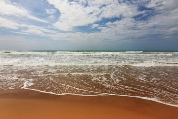 In riva al mare; in spiaggia, sul bagnasciuga in una giornata nuvolosa d’estate