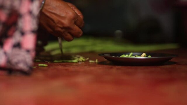 Hands taking beans out of pod. Static, low POV, shallow focus