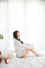 Obraz na płótnie Canvas Portrait beautiful asian girl sitting with clock at white bedroom