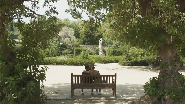 Romantic couple sitting on park bench showing affection