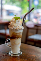 white glace, coffee with ice-cream and whip cream in the coffee shop, with a stainless reusable straw
