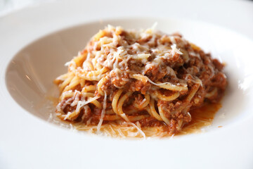 spaghetti Bolognese with minced beef and tomato sauce garnished with parmesan cheese and basil , Italian food