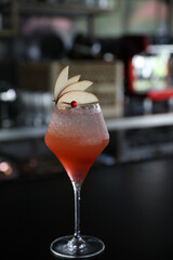 Pink Cocktail glass with ice at a bar counter