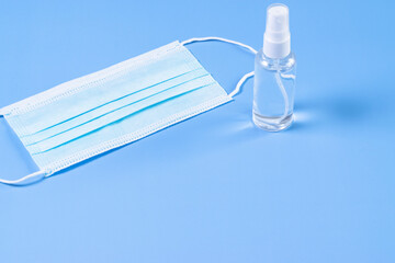 Disposable face masks and disinfectant on a blue background.