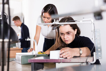 Female architect working on fret saw, creating details for new architectural model in design...