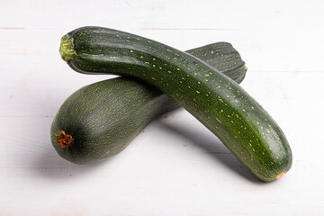 two green zucchini on a white wooden table