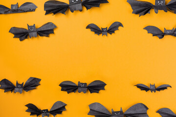 Bats made of paper are arranged on an orange background. Copy space. Flat lay. The concept of Halloween, and holiday decorations