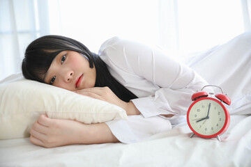 Portrait beautiful asian girl sitting with clock at white bedroom