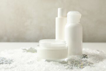 Cosmetics on white table with decorative snow