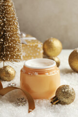 Fototapeta na wymiar Jar of cosmetic cream and Christmas accessories on background with decorative snow