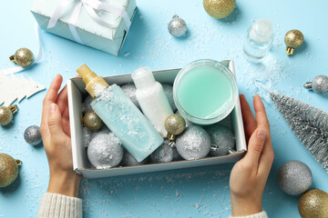 Female hands hold box with winter cosmetics on blue background