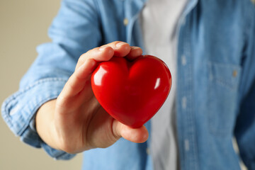 Woman in jean shirt hold red heart, close up