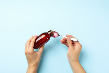 Woman pouring syrup in spoon on blue background - obrazy, fototapety, plakaty