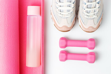 Sneakers, a bottle of water and dumbbells on white background
