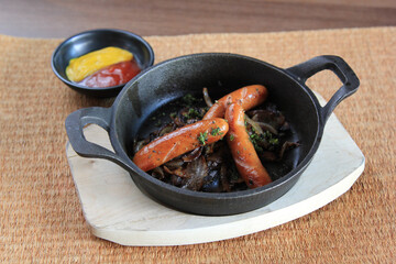 Frying sausage in hot olive oil at home kitchen close up. Top view of preparing crispy red sausages on a cooking pan with boiling oil.