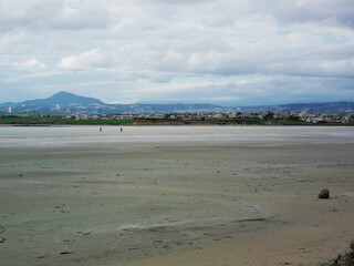 An almost dried out Salt Lake near Larnaka, Cyprus. Two tourists in the distance walking on wet and muddy surface of the lake bottom.