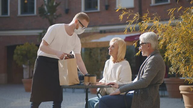 Senior couple sitting on restaurant terrace waiting for takeaway order