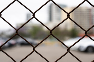chainlink fencing around a car parking area. detail, close up of rusty wire. 