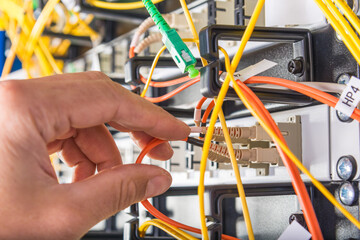 hand of technician plugging in fiber cable into server switch