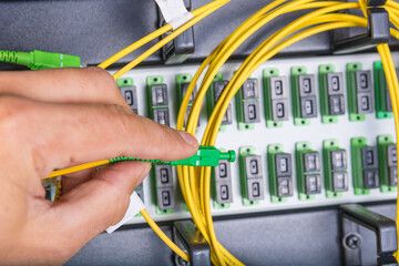 hand of technician plugging in fiber cable into server switch
