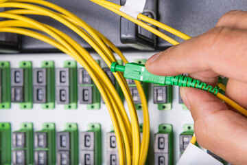 hand of technician plugging in fiber cable into server switch