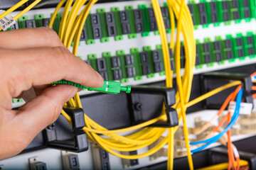 hand of technician plugging in fiber cable into server switch