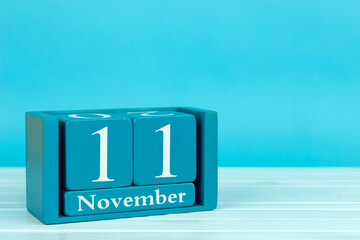 wooden calendar with the date of November 11 on a blue wooden background, World Origami Day; World Shopping Day; International Day for Energy Saving; World Geographic Information Systems Day