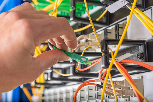 hand of technician plugging in fiber cable into server switch