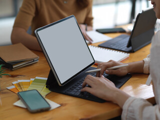 Female student typing on tablet include clipping path while doing group assignment