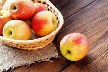 Fresh rustic apples in a basket on the table. Water drops on apples lit by the sun.