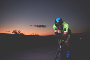 triathlon athlete riding bike fast at night