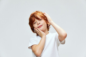cute redhead boy holding hands on face white t-shirt studio