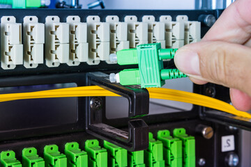 Hand of computer engineer connecting fiber optic cable in server