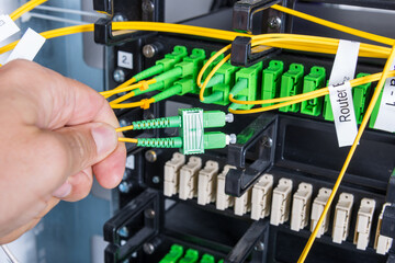 Hand of computer engineer connecting fiber optic cable in server