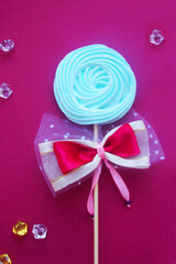 Birch meringue on a stick with a bow on a pink background.