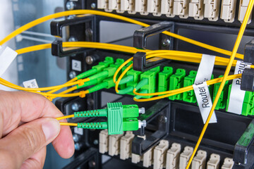 Hand of computer engineer connecting fiber optic cable in server