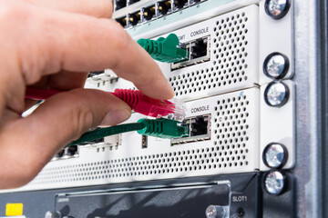 Hand of computer engineer connecting network cable in server cab
