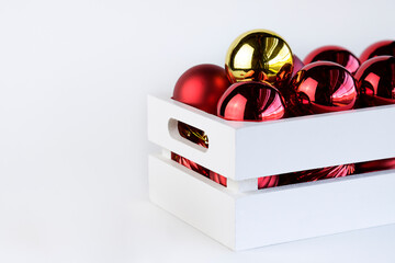 Red and golden christmas balls inside a white wooden box with copy space