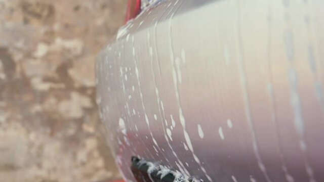 Water and soap foam dripping down the backside of a car being washed