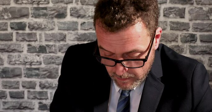 Business man with glasses aking notes and using calculator on desk in office
