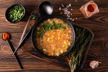 red lentil and corn soup with herbs and paprika in a black bowl, top viiew