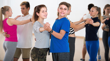 Positive children studying dancing with partner at dance school.