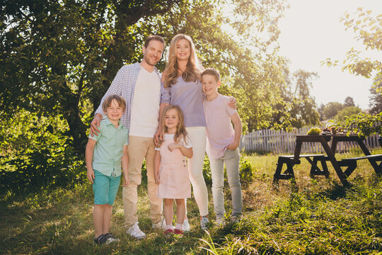 Full length photo of charming loving foster family have fun summer countryside garden relax mom mommy dad daddy hug embrace small kids under green tree outside
