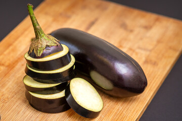 Fresh sliced eggplant on wooden cutting board isolated on black. Cooking ingredients